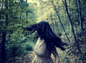 Scared young woman running through a forest at night